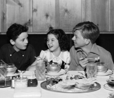 Niños en una mesa con comida.