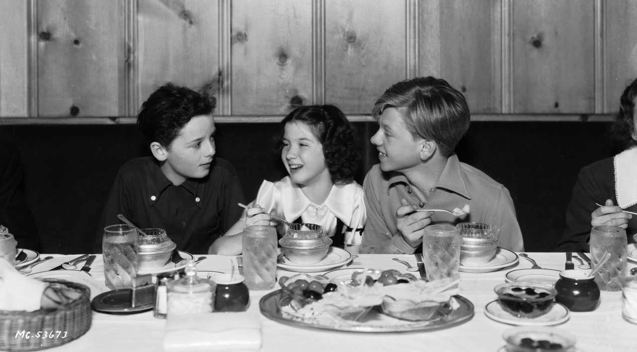 Niños en una mesa con comida.